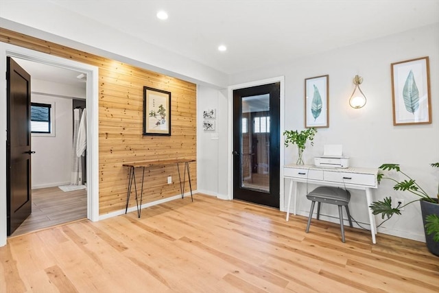 entrance foyer with recessed lighting, baseboards, wood walls, and light wood finished floors