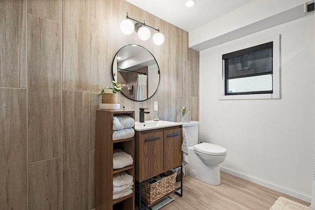 bathroom with baseboards, vanity, toilet, and wood finished floors
