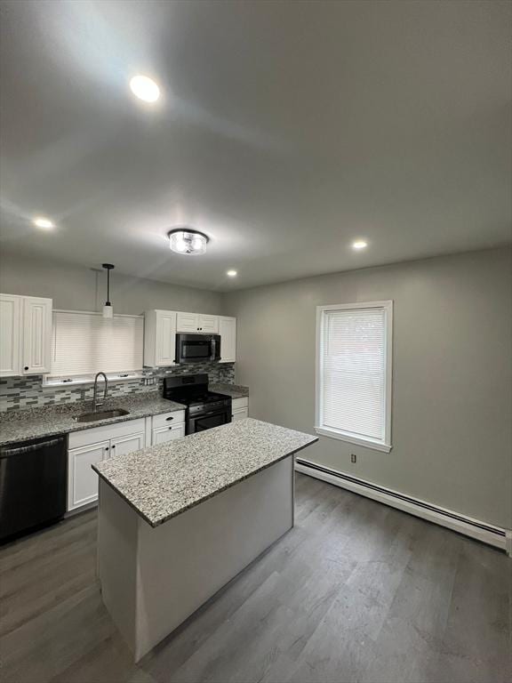 kitchen featuring black appliances, a sink, backsplash, light stone counters, and a kitchen island