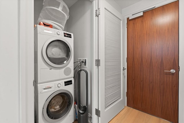 laundry area featuring stacked washing maching and dryer and light hardwood / wood-style floors