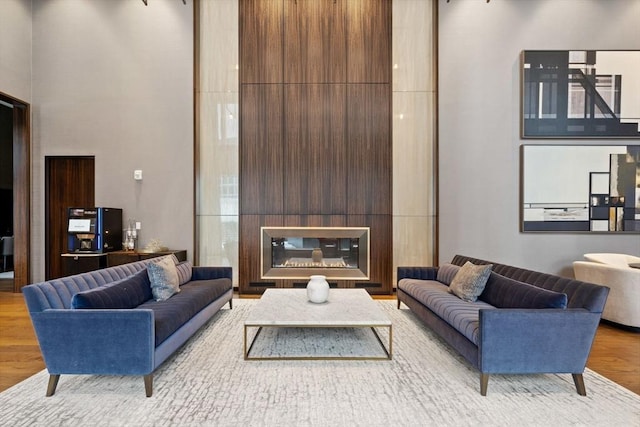 living room with a towering ceiling, wood-type flooring, and a large fireplace