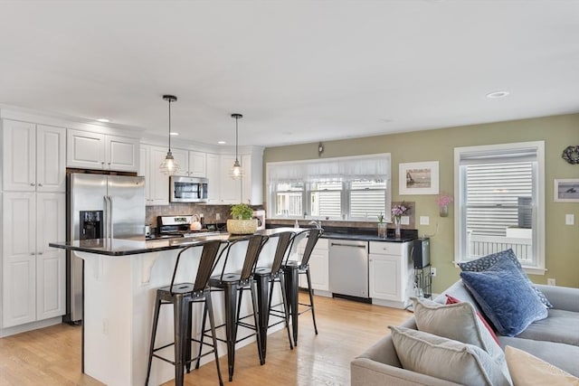 13 11th St W, Salisbury, MA 01952 - kitchen with appliances with stainless steel finishes, open floor plan, a breakfast bar, white cabinets, and recessed lighting