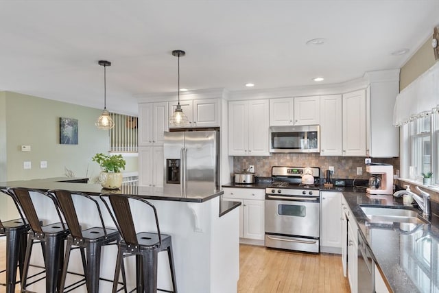 13 11th St W, Salisbury, MA 01952 - kitchen with stainless steel appliances, a sink, a breakfast bar, white cabinets, and recessed lighting