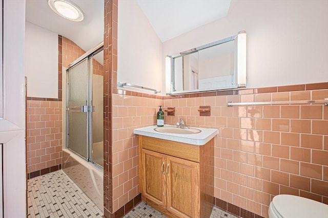 bathroom featuring lofted ceiling, vanity, tile walls, and walk in shower