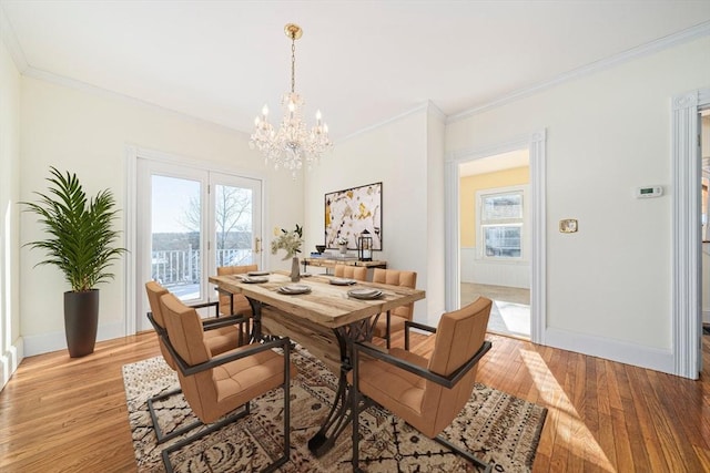 dining room featuring crown molding, light hardwood / wood-style flooring, plenty of natural light, and a notable chandelier