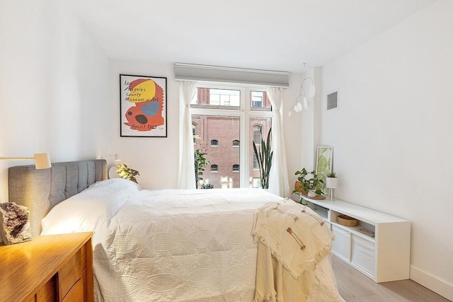 bedroom with visible vents, light wood-type flooring, and baseboards