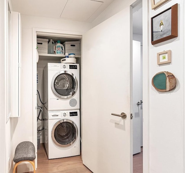 clothes washing area featuring laundry area, stacked washer and clothes dryer, and light wood-type flooring