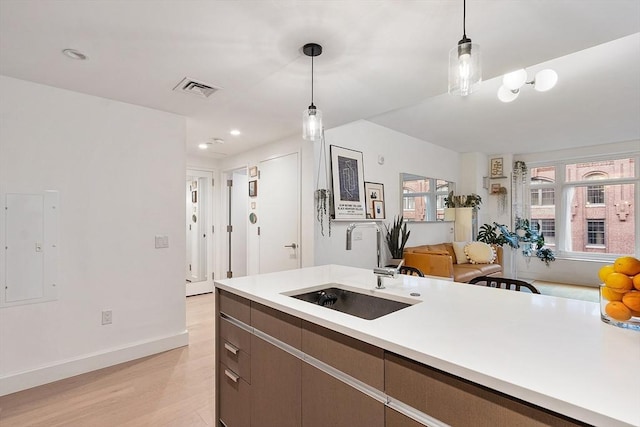 kitchen with visible vents, light wood-type flooring, decorative light fixtures, light countertops, and baseboards