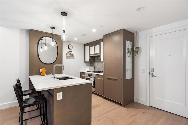 kitchen featuring a sink, a kitchen bar, stainless steel appliances, and light wood finished floors