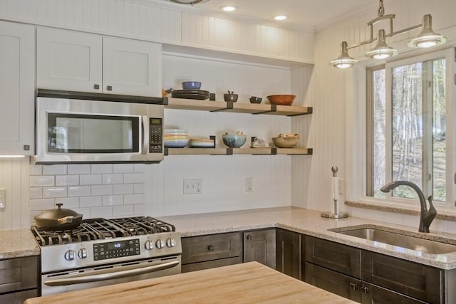 kitchen with a wealth of natural light, stainless steel appliances, a sink, and light stone countertops