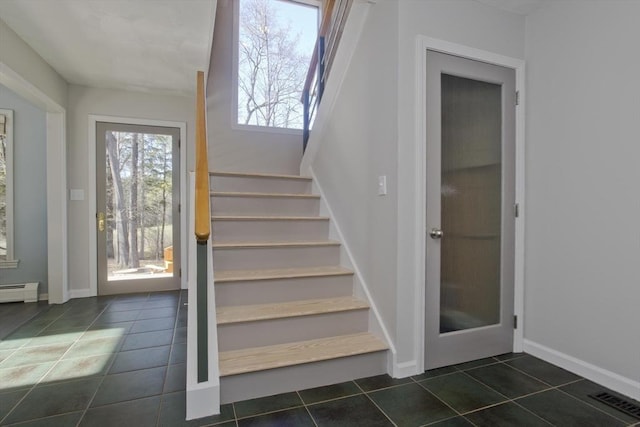staircase featuring a baseboard radiator, baseboards, visible vents, and tile patterned floors