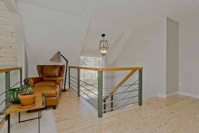 living area with lofted ceiling, baseboards, an upstairs landing, and wood finished floors