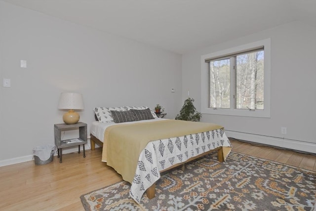 bedroom featuring light wood-style floors, baseboards, and baseboard heating