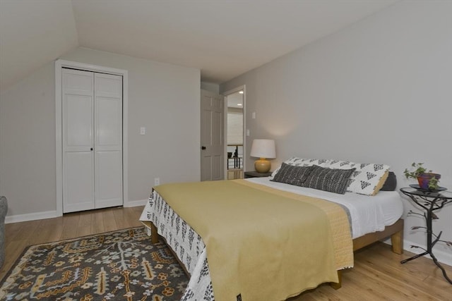 bedroom with baseboards, vaulted ceiling, and wood finished floors