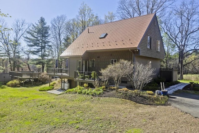 back of property featuring a deck and a lawn