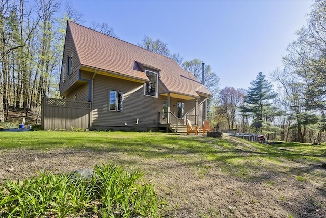 back of property with a shingled roof and a yard