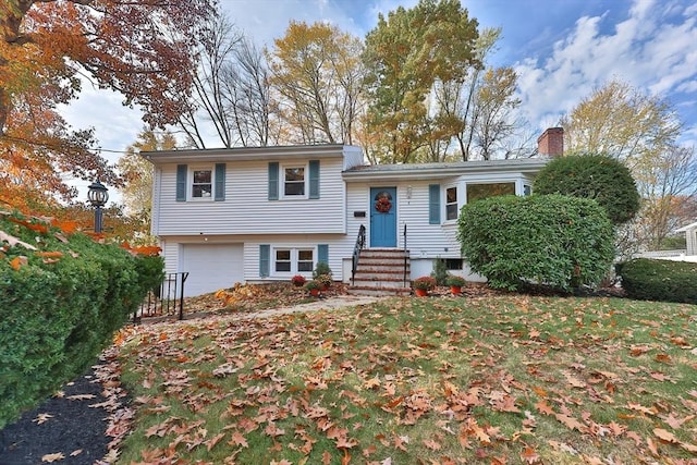 tri-level home featuring a garage and a front yard