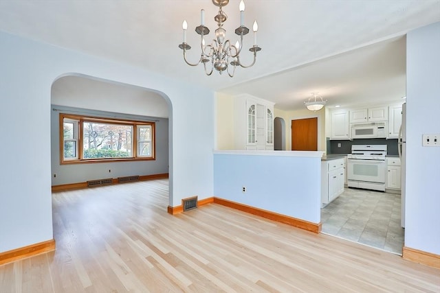 kitchen with a chandelier, hanging light fixtures, white appliances, light hardwood / wood-style floors, and white cabinets