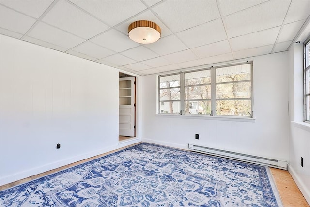 spare room with wood-type flooring, a drop ceiling, and baseboard heating