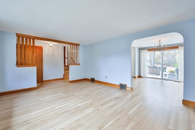 unfurnished living room featuring a chandelier and light wood-type flooring