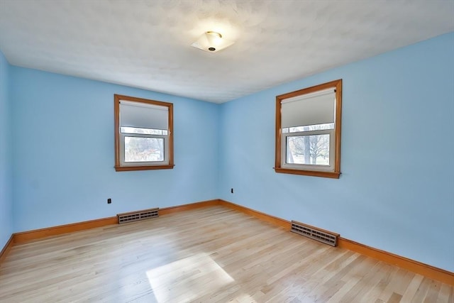 empty room with plenty of natural light and light hardwood / wood-style floors