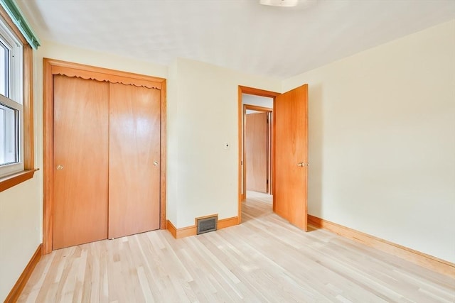 unfurnished bedroom featuring light hardwood / wood-style flooring and a closet