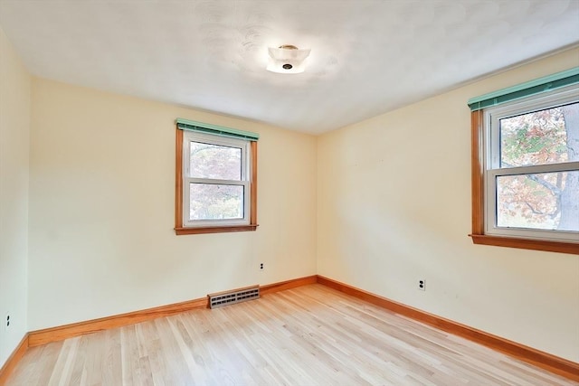 empty room with plenty of natural light and light hardwood / wood-style floors