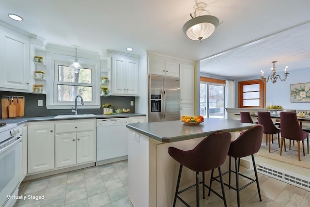 kitchen with white cabinetry, a center island, sink, and white appliances