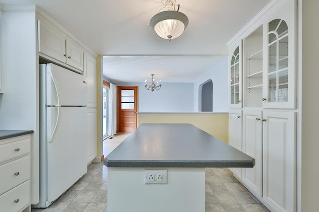 kitchen featuring pendant lighting, a center island, white fridge, and white cabinets