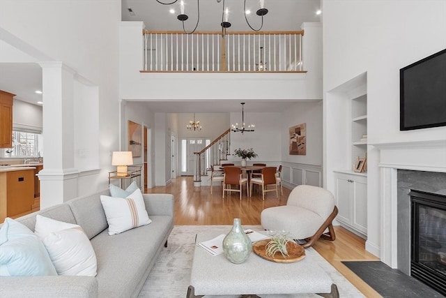 living area with light wood finished floors, a fireplace with flush hearth, built in shelves, and a chandelier