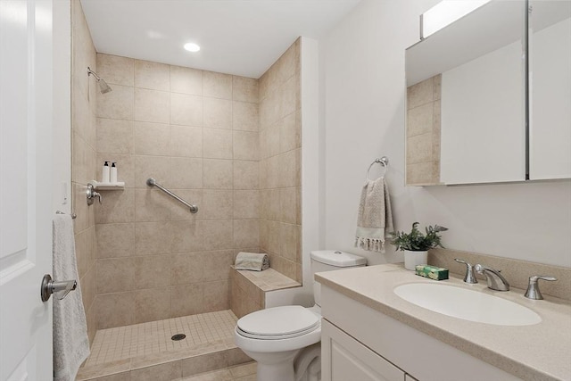 bathroom with toilet, a tile shower, and vanity