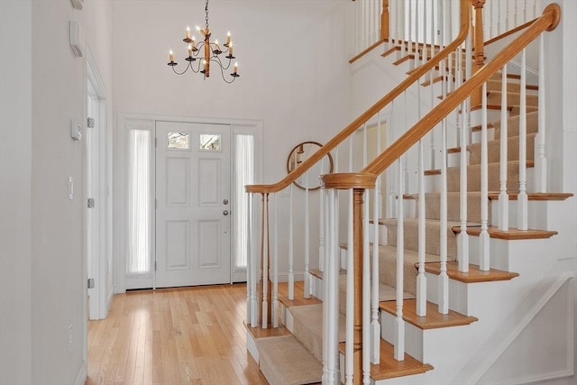 entrance foyer with a high ceiling, light wood-type flooring, and a notable chandelier