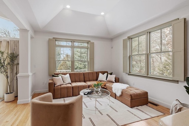 living area with ornate columns, vaulted ceiling, baseboards, and light wood finished floors