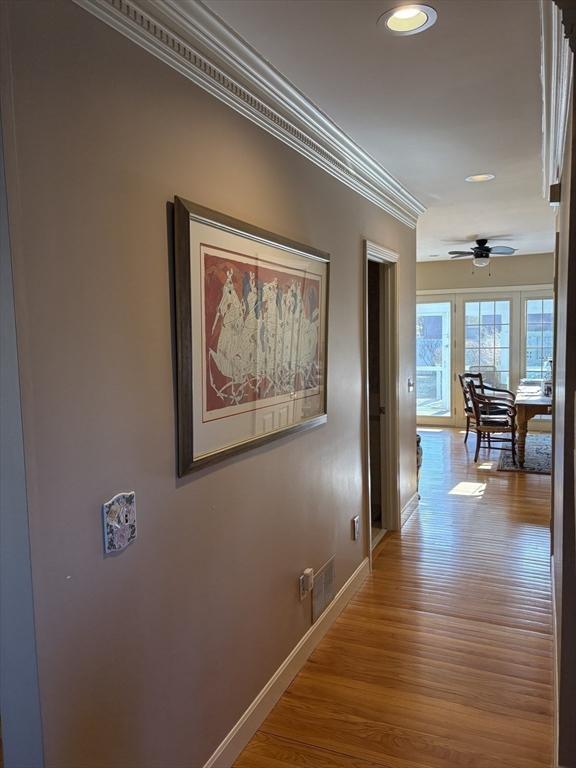 hallway with ornamental molding and light hardwood / wood-style floors