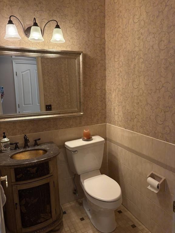 bathroom featuring vanity, toilet, tile patterned flooring, and tile walls