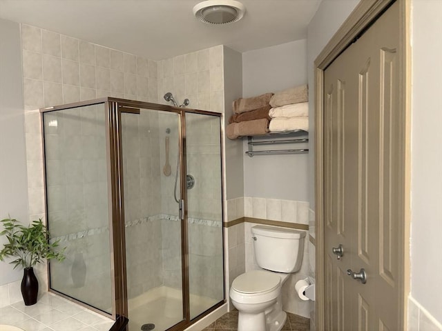 bathroom with tile walls, an enclosed shower, and toilet