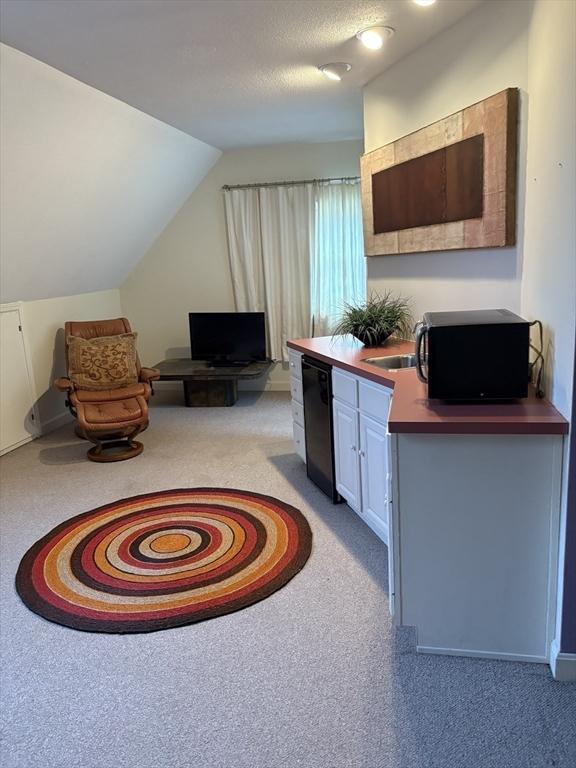 carpeted home office with vaulted ceiling and a textured ceiling