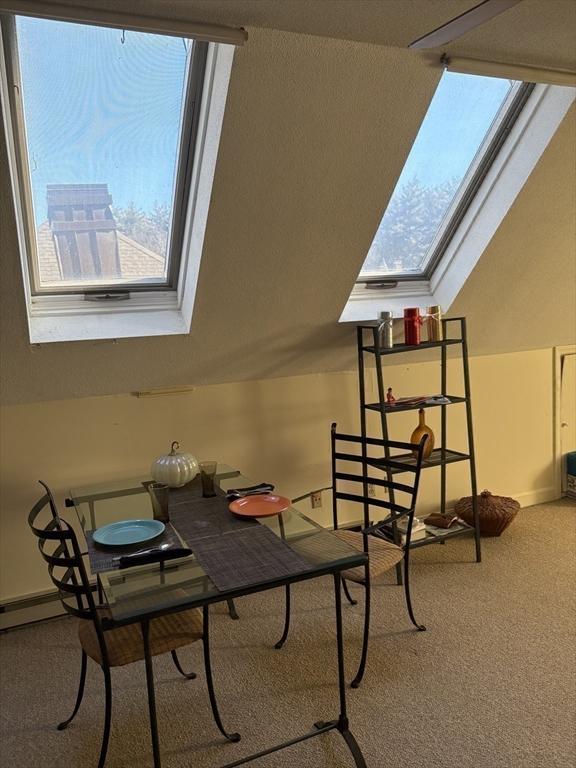 interior space with plenty of natural light, vaulted ceiling with skylight, and carpet