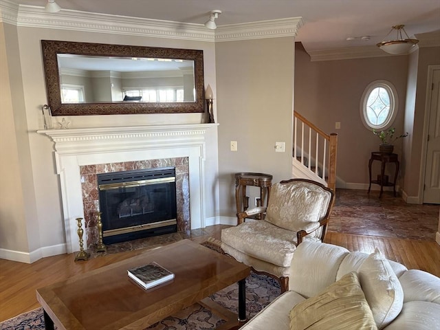 living room featuring a tiled fireplace, ornamental molding, and wood-type flooring