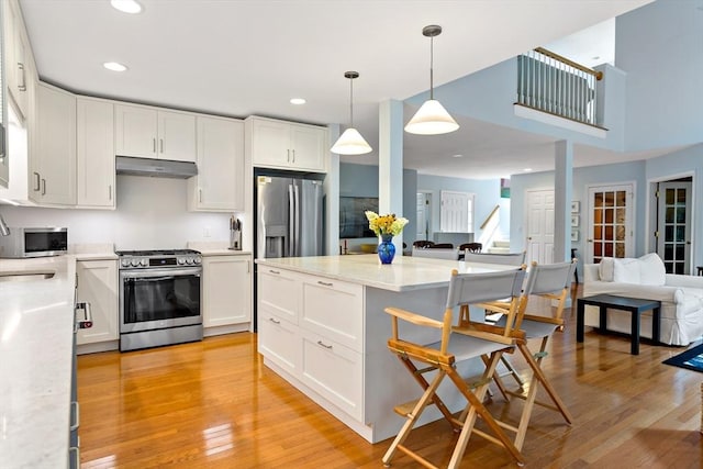 15 Berrywood Ct Unit 15, Bourne, MA 02532 - kitchen with a breakfast bar area, under cabinet range hood, open floor plan, stainless steel appliances, and white cabinetry
