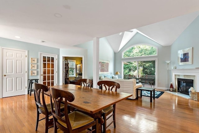 15 Berrywood Ct Unit 15, Bourne, MA 02532 - dining room with a glass covered fireplace, baseboards, vaulted ceiling, and light wood-style flooring