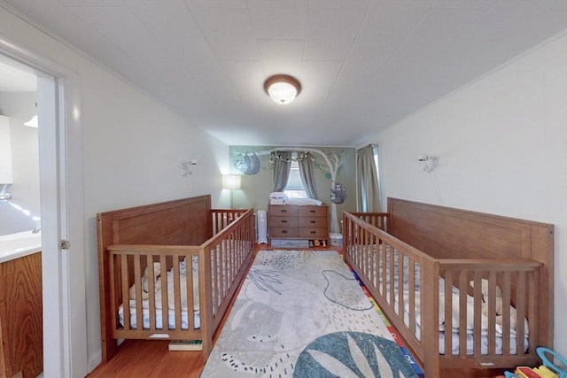bedroom with wood finished floors and a crib