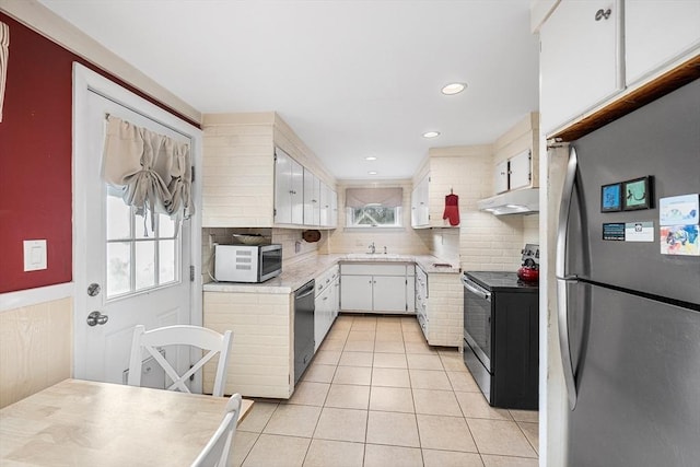 kitchen with freestanding refrigerator, range with electric cooktop, under cabinet range hood, a sink, and light tile patterned floors