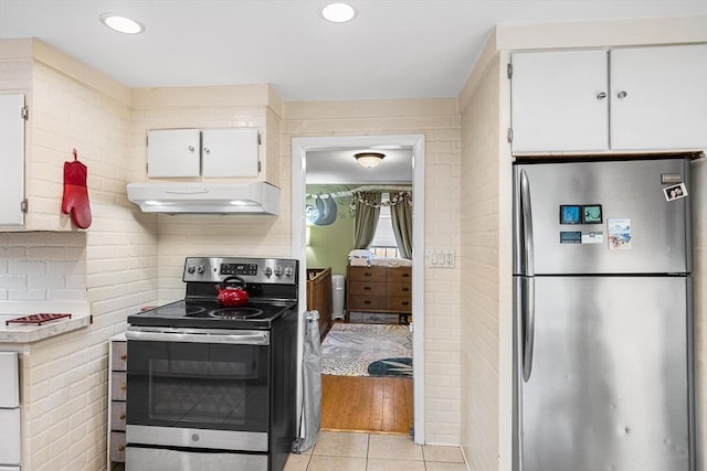 kitchen featuring stainless steel appliances, under cabinet range hood, white cabinetry, and light tile patterned floors
