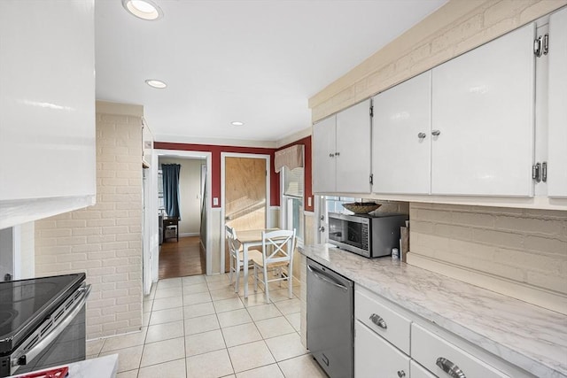 kitchen with appliances with stainless steel finishes, light tile patterned floors, white cabinets, backsplash, and light stone counters