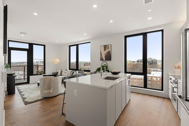 1515 Commonwealth Ave Unit 302, Boston, MA 02135 - kitchen featuring modern cabinets, light wood-style floors, a kitchen island with sink, recessed lighting, and open floor plan