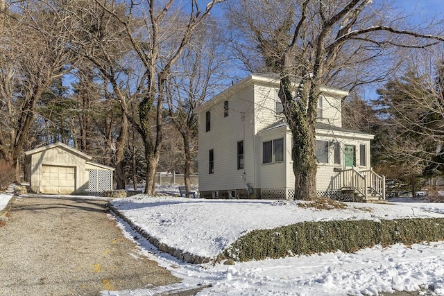 view of snowy exterior featuring an outbuilding and a garage