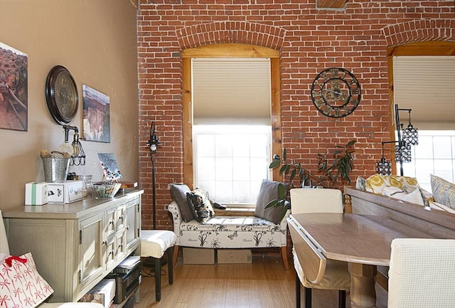 interior space with light wood-type flooring, a healthy amount of sunlight, and brick wall