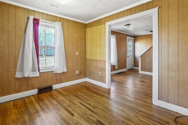 unfurnished room with wood walls, hardwood / wood-style floors, and crown molding