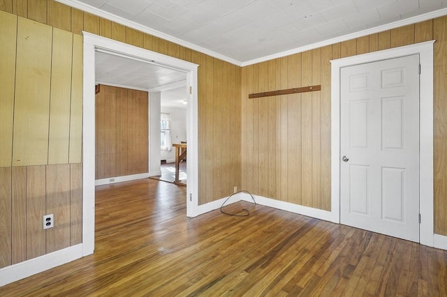 unfurnished room featuring wood-type flooring, wood walls, and crown molding